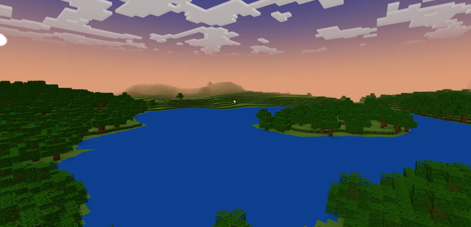 A wide blue lake ringed by dense blocky forest under heavy sunset clouds.
