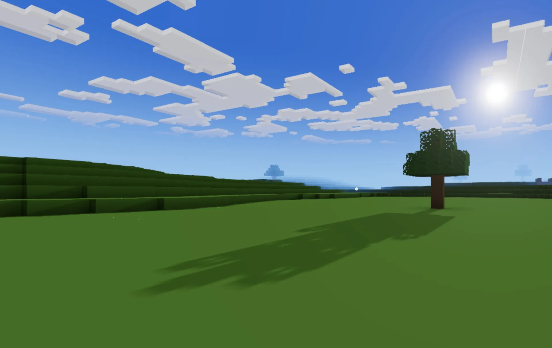 A lone blocky tree casting a long shadow over open green plains under a bright blue sky with drifting cloud slabs.